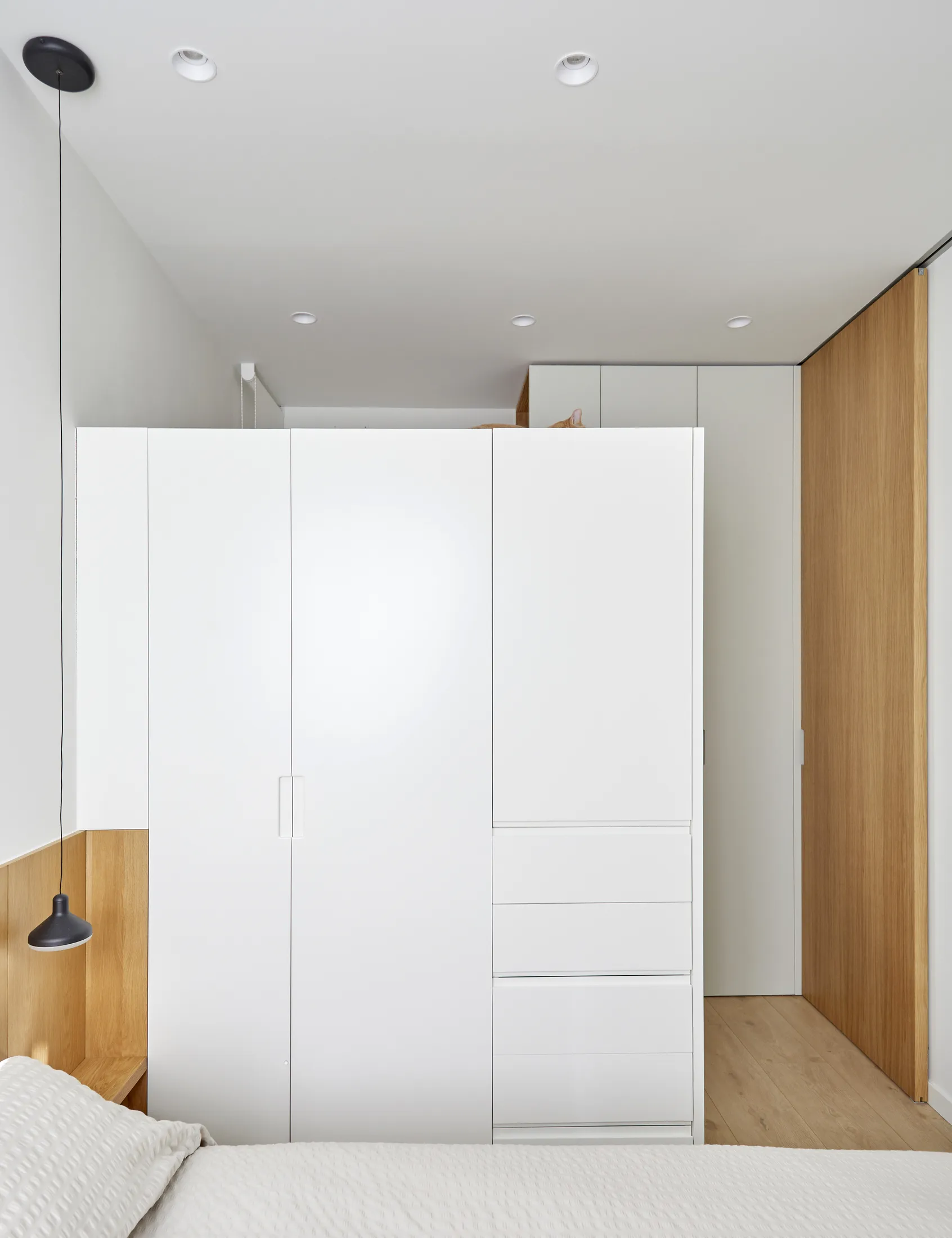 White wardrobe stopping below the ceiling between the bedroom and office in the Madrid apartment